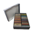 A large open cassette tape storage box with multiple cassette tapes in their original cases, lying in an organized fashion.