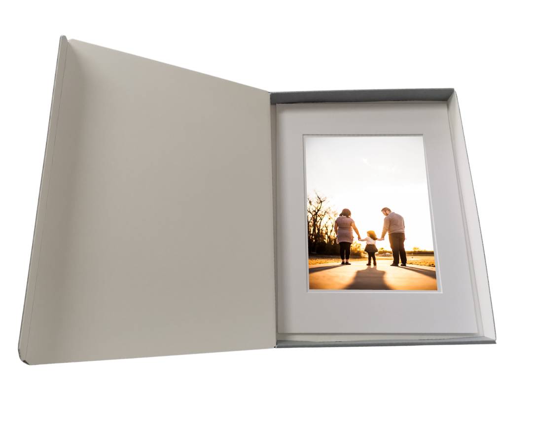 A hinged lidded archival print box with photo of family holding hands in a white mat frame