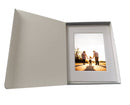 A hinged lidded archival print box with photo of family holding hands in a white mat frame